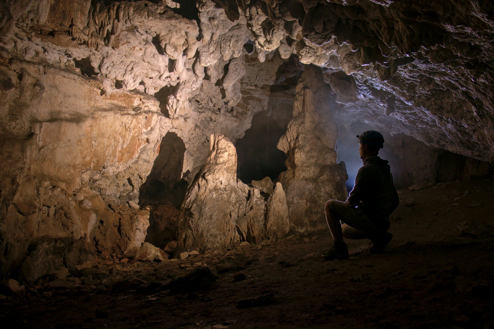 A guided cave explorer studying mineral formations underground