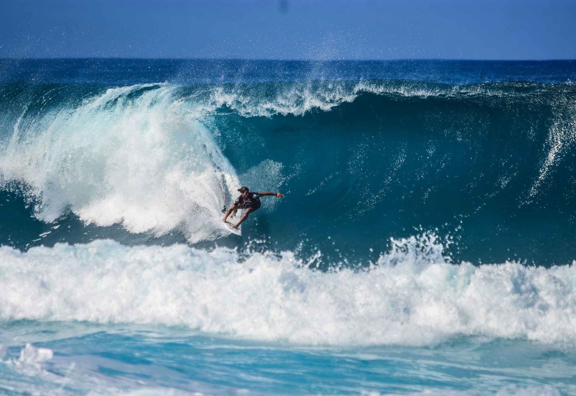 A surfer carving across a powerful Pacific wave