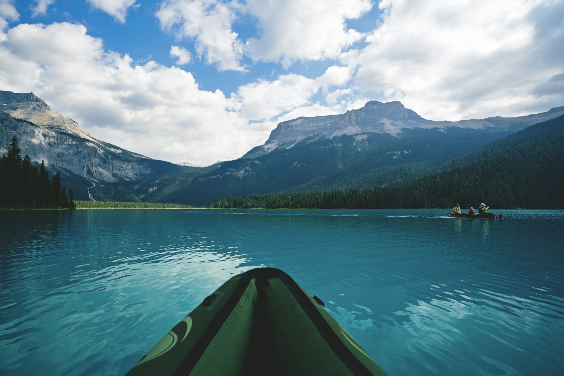 Kayaking across a turquoise mountain lake in British Columbia